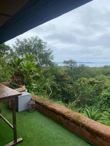a balcony with green grass and a view of the forest at Sea view hills bungalow in Torio
