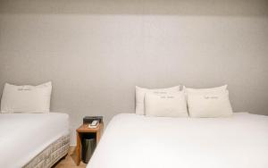 two beds with white sheets and pillows in a room at Vov Hotel in Busan