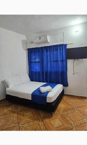 a bed in a room with a blue curtain at Hotel Zulan in Tolú