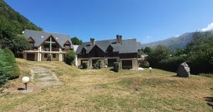 a large house on a hill with mountains in the background at Joli triplex 3 étoiles, avec jardin et cheminée in Génos