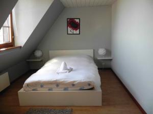 a bedroom with a white bed in a attic at Gite Des Trois in Orschwiller