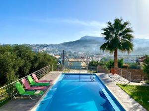 una piscina con 2 sillas y una palmera en Sea view Apartment 5 with roof top terrace, Almyrida, en Almyrida