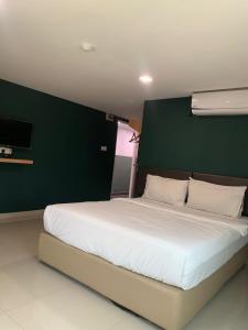 a bedroom with a large white bed with a green wall at Room V by SECOM Jalan Megat in Batu Pahat