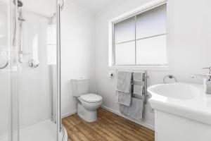 a white bathroom with a toilet and a sink at It's Easy! Space and comfort in Wanaka