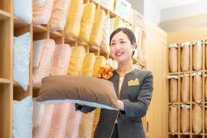 a woman is holding a pillow in a store at Super Hotel Osaka Natural Hot Springs in Osaka