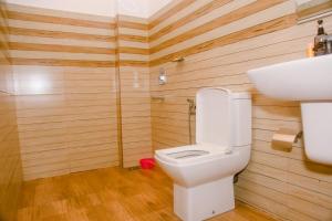 a bathroom with a toilet and a sink and wooden walls at St Kilda Hotel & Restaurant in Ahangama