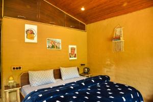- une chambre avec un lit et un mur jaune dans l'établissement Monkey Mud House and Camps, Bir, à Bir