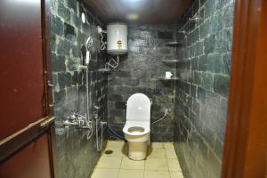 a small bathroom with a toilet in a brick wall at Monkey Mud House and Camps, Bir in Bīr
