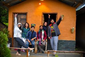a group of people standing in front of a house at Monkey Mud House and Glamps, Bir in Bīr