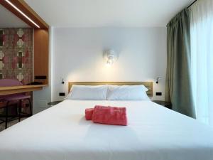 a large white bed with a red object on it at Stic Urban Hotel & SPA in San Antonio