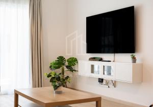a living room with a table and a tv on a wall at Fully Furnished 1BR Apartment with Stunning Interior in Dubai