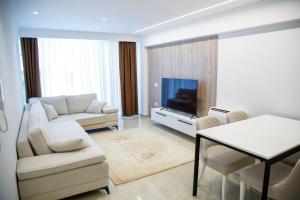 ein Wohnzimmer mit einem Sofa, einem TV und einem Tisch in der Unterkunft shomez apartaments in Tirana