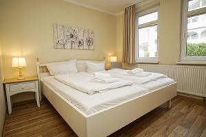 ein großes weißes Bett in einem Zimmer mit Fenster in der Unterkunft mit Meerblick und Balkon, gratis Nutzung vom AHOI Erlebnisbad und Sauna in Sellin - Meeresblick FeWo 38 in Göhren