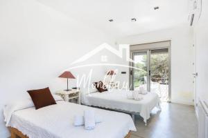 a white room with two beds and a window at Villa Colom in Son Carrio