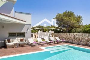 a backyard with a pool and chairs and a house at Villa Colom in Son Carrio