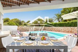 a dining room with a table and a swimming pool at Villa Colom in Son Carrio