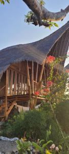 a building with a thatched roof with flowers on it at Penida Bambu Green in Nusa Penida