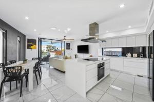 una cocina con armarios blancos y una mesa con sillas. en Luxury Modern Waterfront House, en Gold Coast