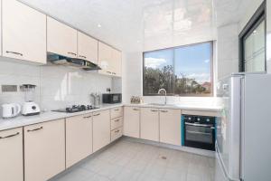 a kitchen with white cabinets and a large window at Home away from home in Nairobi