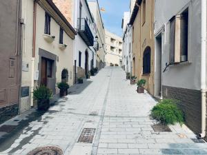 an empty alley with buildings and potted plants at Hauzify I Apartament Monlema in Sant Feliu de Guíxols