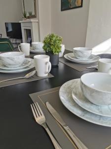 una mesa negra con platos blancos y cubiertos en Contractors Home Free Parking 5 MINS To City Centre, en Hull