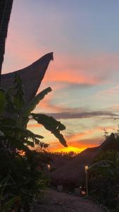 a sunset with a bunch of leaves in front of a house at Penida Bambu Green in Nusa Penida