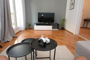 ein Wohnzimmer mit 3 schwarzen Tischen und einem TV in der Unterkunft Minimal apartment in koukaki in Athen