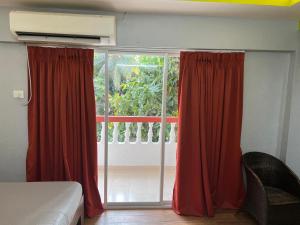 - une chambre dotée d'une grande fenêtre avec des rideaux rouges dans l'établissement mello rosa appartment arpora, à Vieux-Goa