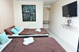 two beds in a room with a flat screen tv at Angler's Hub & Resort in Oslob