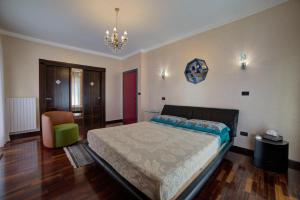 ein Schlafzimmer mit einem Bett, einem Stuhl und einem Kronleuchter in der Unterkunft Villa Alba in Petacciato