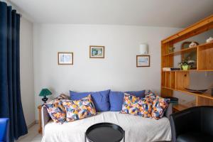 ein Wohnzimmer mit einer blauen Couch mit Kissen in der Unterkunft Logement Coquelicot - 6 personnes in Hillion