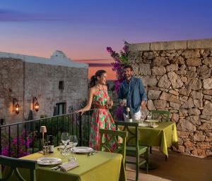 Ein Mann und eine Frau stehen auf einem Balkon mit Weingläsern in der Unterkunft Hotel Masseria Fontanelle in Ugento