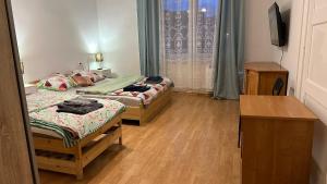 - une chambre avec 2 lits, un bureau et une télévision dans l'établissement Pokoje w Gołdapi, à Gołdap