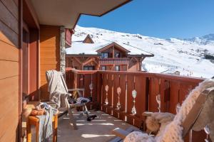 a balcony with rocking chairs and a snow covered mountain at Résidence Pierre & Vacances Premium Les Alpages de Reberty in Les Menuires