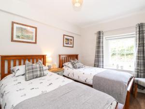 Un dormitorio con dos camas y una ventana. en Orchard Cottage, en Windermere