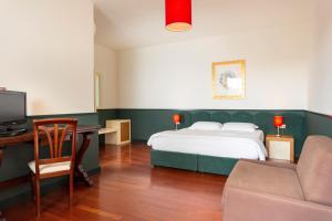 1 dormitorio con 1 cama y escritorio con TV en Hotel Ghalà, en Galatone