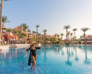 Eine Frau steht im Wasser in einem Resortpool. in der Unterkunft The Grand Resort in Hurghada