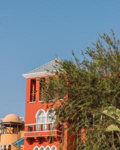 ein rotes Gebäude mit einem Baum davor in der Unterkunft The Grand Resort in Hurghada