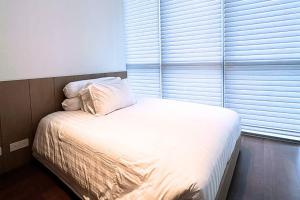 a bed with white sheets and pillows next to a window at Lux & Spacious 3BR in Central Jakarta in Jakarta