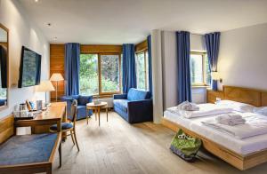 um quarto de hotel com uma cama, uma secretária e uma cadeira em Hotel Brandauers Villen Superior em Strobl