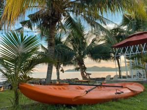 a orange kayak sitting on the grass next to palm trees at Windy Seaview Resort in Chao Lao Beach
