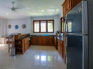 a kitchen with wooden cabinets and a stainless steel refrigerator at 3 Bedroom Private House in Gili Trawangan