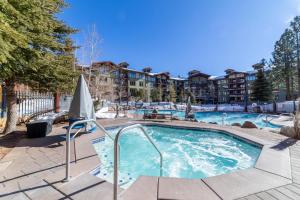 ein Pool mit Sonnenschirm und ein Gebäude in der Unterkunft 506 Village Condo Steps to Gondola in Mammoth Lakes