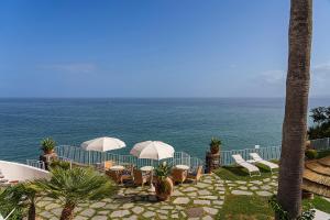 eine Terrasse mit Stühlen, Sonnenschirmen und dem Meer in der Unterkunft Hotel Continental Mare in Ischia