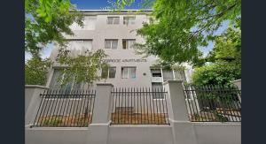 Un edificio blanco con una valla delante. en Knightsbridge Apartments, en Melbourne