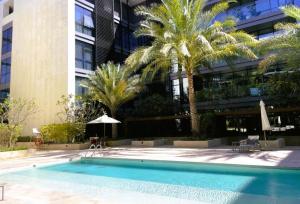 a swimming pool in front of a building with palm trees at City Walk, Al Wasl, Jumeirah - Mint Stay in Dubai