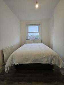 a bed in a white room with a window at Battersea Park apartments in London