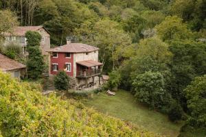 a large red house in the middle of a forest at Casa Muíñovedro in Chantada