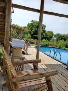 una terraza de madera con una silla y una piscina en NKUNDWA NILE VIEW LODGE, en Wanseko