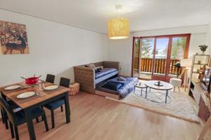 un soggiorno con un tavolo e un divano di Charmant appartement au centre a Crans-Montana